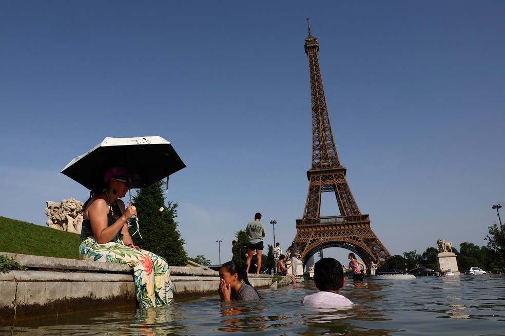 Pessoas se refrescam na fonte do Trocadéro, diante da Torre Eiffel, durante uma onda de calor em Paris, na França. — Foto: Abdul Saboor/Reuters