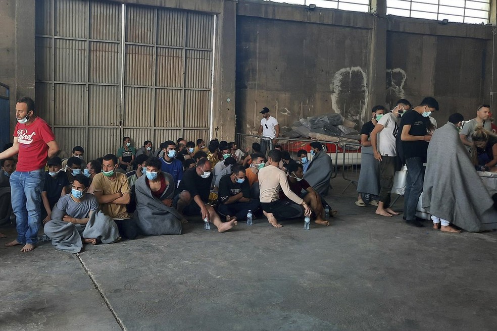 Sobreviventes de um naufrágio sentam-se em um armazém no porto da cidade de Kalamata, cerca de 240 quilômetros (150 milhas) a sudoeste de Atenas — Foto: AP