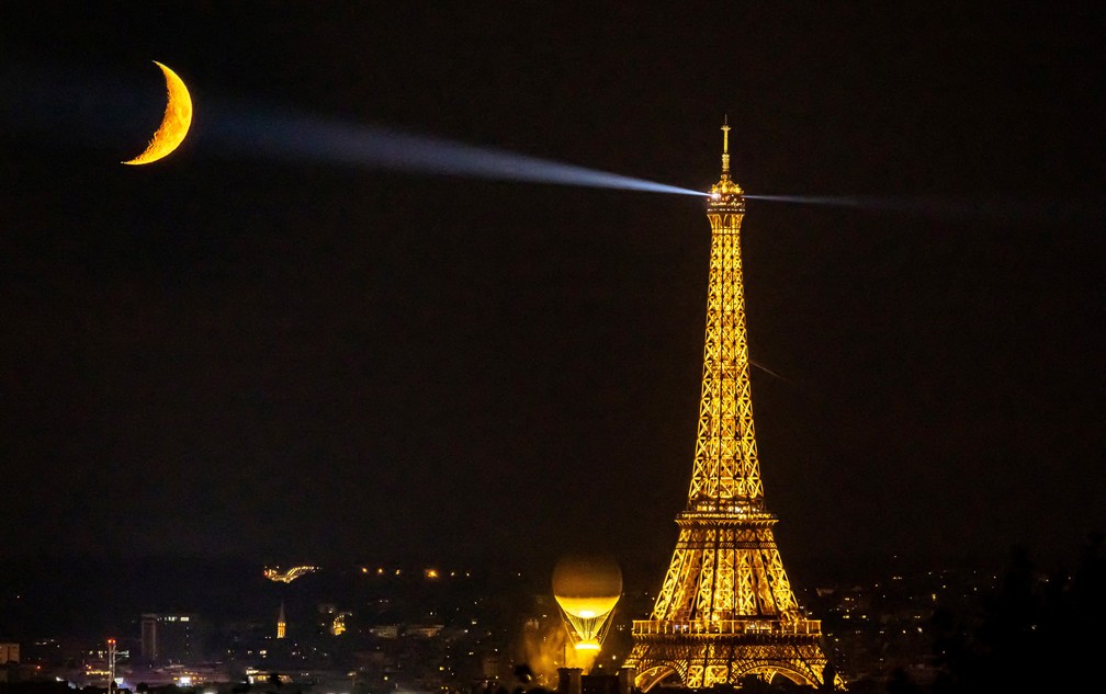 A lua é vista atrás da Torre Eiffel e do caldeirão olímpico — Foto: Christian Hartmann/Reuters