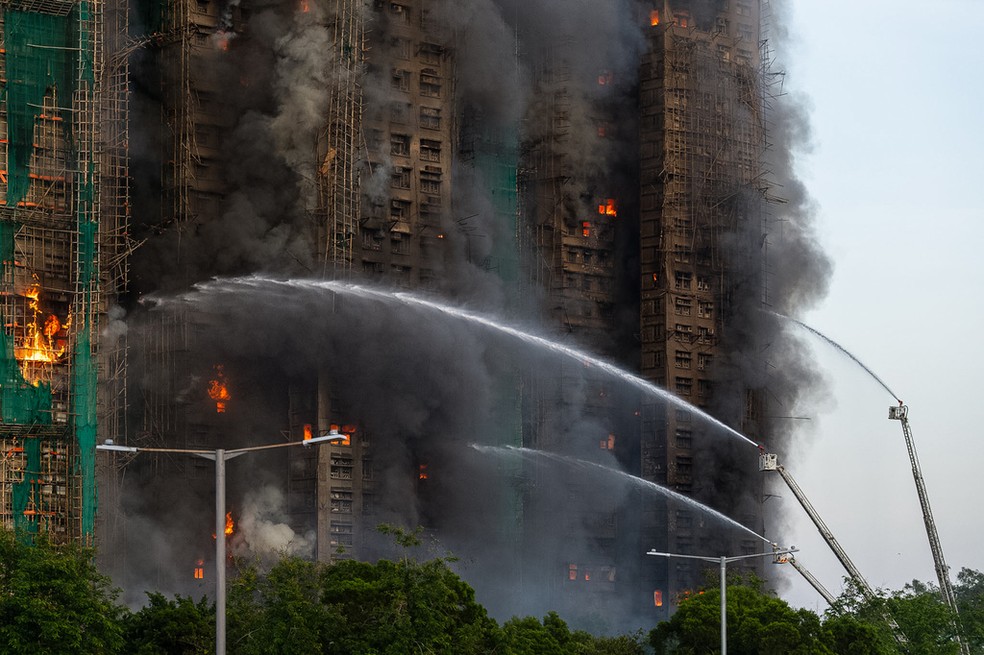 Bombeiros trabalhando em conjunto para tentar conter as chamas — Foto: AP Photo/Chan Long Hei
