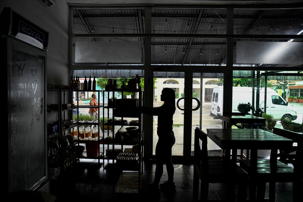 Mulher em restaurante sem luz após apagão atingir Cuba, em 18 de outubro de 2024. — Foto: Norlys Perez/ Reuters