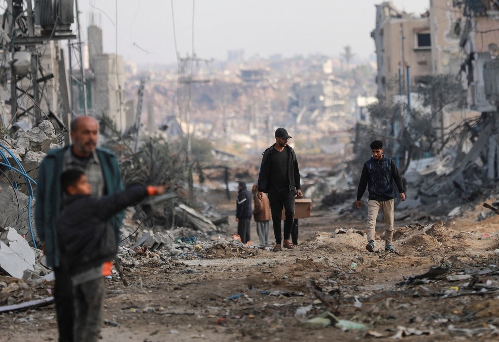 Palestinos caminham por cidade destruída na região central da Faixa de Gaza, em 29 de novembro de 2024 — Foto: REUTERS/Abd Elhkeem Khaled