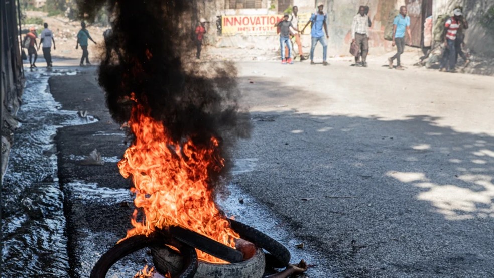 Cadáver arde sob pneus em uma rua do centro de Porto Príncipe, no dia 9 de fevereiro de 2026 — Foto: Clarens Siffroy via BBC