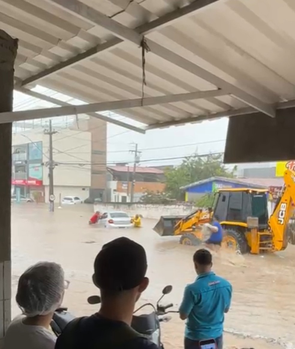 Carro fica preso em alagamento e precisa ser guinchado por trator — Foto: Reprodução