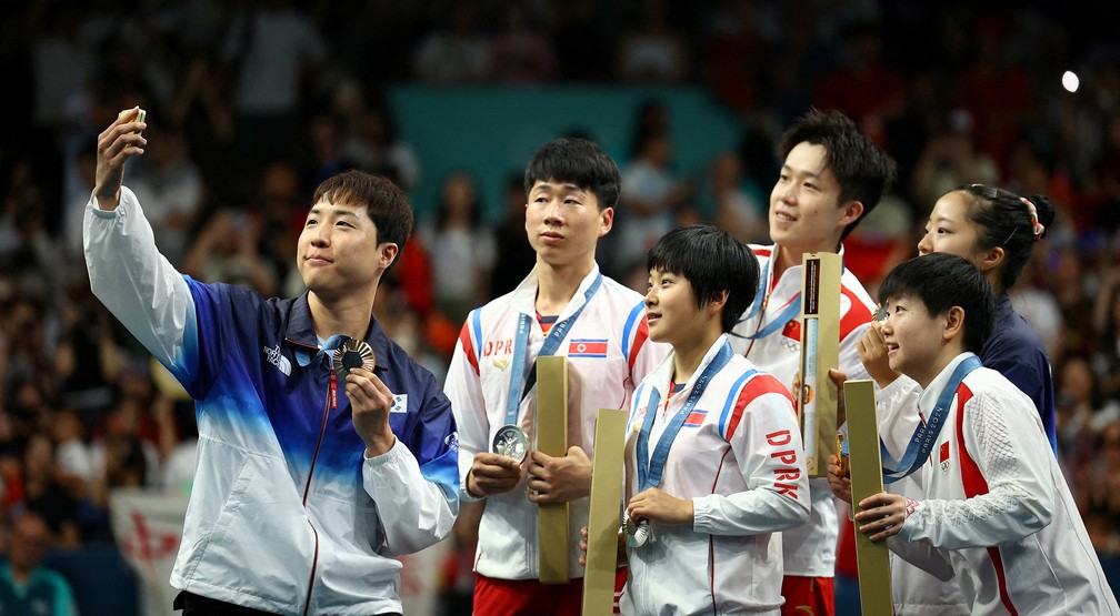 Espírito olímpico: atletas da Coreia do Sul, da Coreia do Norte e da China fazem selfie juntos no pódio do torneio misto de tênis de mesa por equipes — Foto: Kim Hong-Ji/Reuters