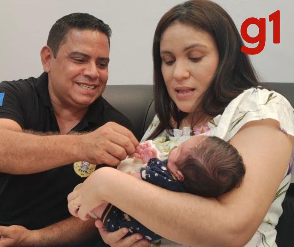 O investigador Ademar e a mãe Mayara brincando com João Pedro durante a visita à delegacia em agradecimento, nesta quarta-feira (19) — Foto: Polícia Civil