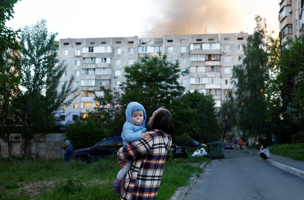 Uma mulher segura uma criança no local dos ataques com mísseis e drones russos, em meio ao ataque da Rússia à Ucrânia, em Kiev. — Foto: Valentyn Ogirenko / Reuters