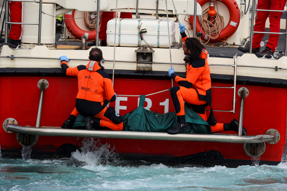 Mergulhadores com o primeiro corpo resgatado em navio da Guarda Costeira — Foto: REUTERS/Louiza Vradi