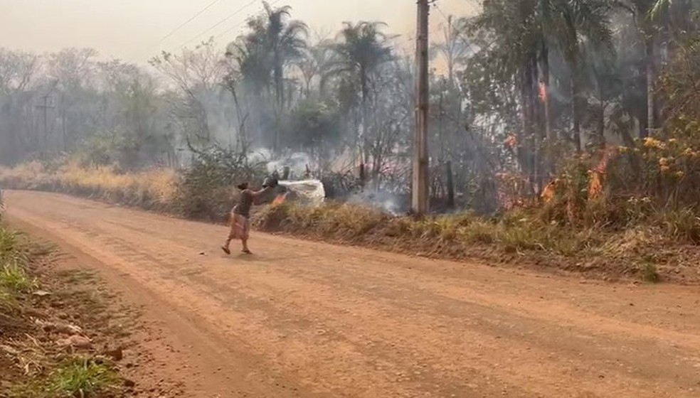 Moradora tenta apagar fogo com balde cheio de água. — Foto: Vinícius Souza/TV Morena