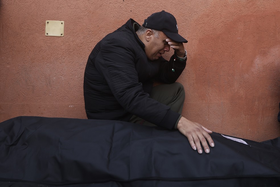 Homem se emociona ao ver ente falecido na frente de mesquita na Faixa de Gaza em 23 de dezembro de 2023 — Foto: Mohammed Dahman/Associated Press