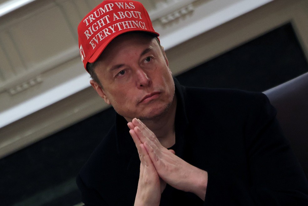 Elon Musk durante reunião na Casa Branca com boné exaltando Trump — Foto: REUTERS/Carlos Barria