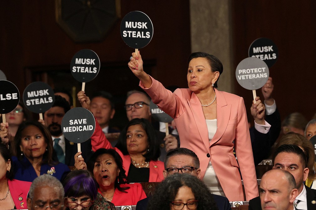 Democratas seguram cartazes de protesto durante o discurso do presidente dos Estados Unidos, Donald Trump, em uma sessão conjunta do Congresso, no plenário da Câmara do Capitólio dos EUA, em Washington, D.C., em 4 de março de 2025. — Foto: Win McNamee/Pool via REUTERS