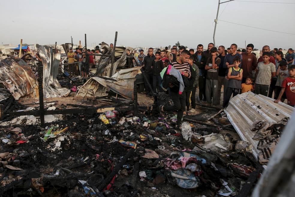 Palestinos observam destroços de acampamento após bombardeio israelense em Rafah — Foto: Jehad Alshrafi/AP Photo
