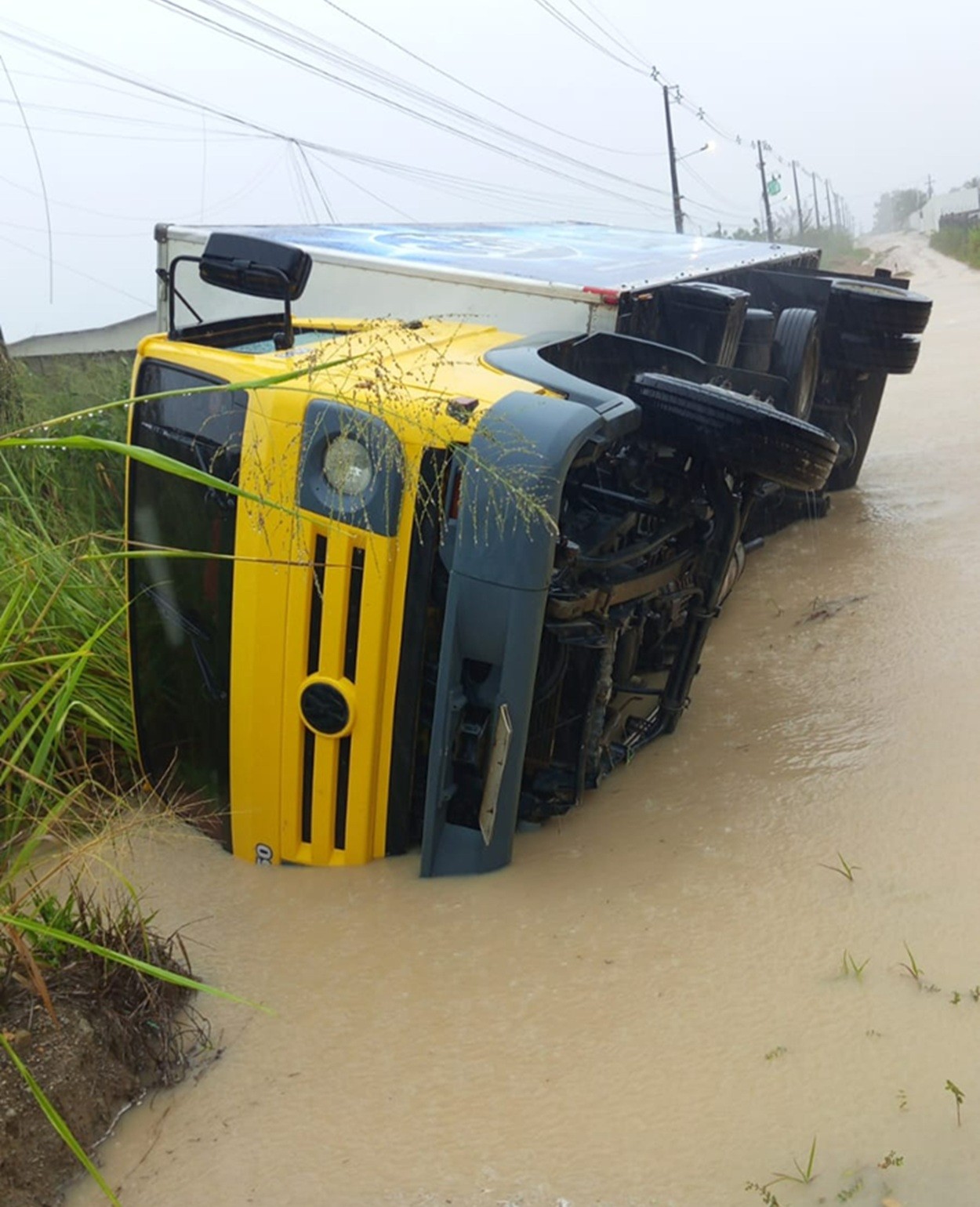 Caminhão carregado de produtos de limpeza tomba em estrada alagada na Grande Natal