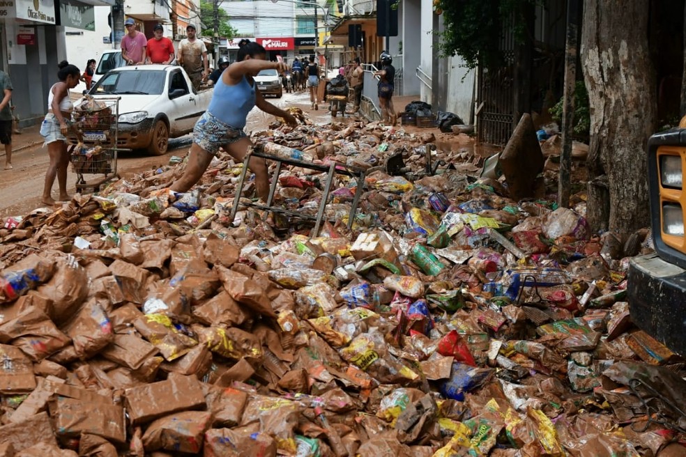Pessoas recolhendo alimentos sujos de lama após chuva forte em Mimoso do Sul, Espírito Santo — Foto: Fernando Madeira/Rede Gazeta