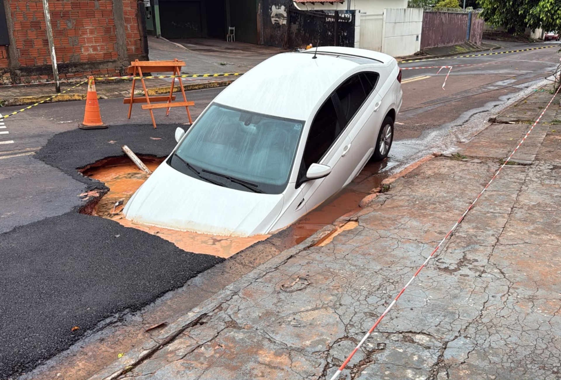 Automóvel afunda em cratera aberta no asfalto após temporal em Campo Grande