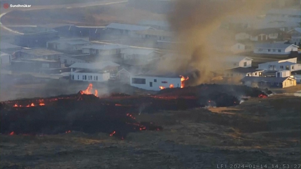 Lava de um vulcão em erupção na Islândia consome uma residência perto da cidade de Grindavik, no sudeste da Islândia, neste domingo, 14 de janeiro de 2024. A comunidade foi evacuada durante a noite. — Foto: LIVEFROMICELAND.IS via AP