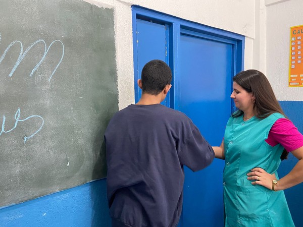 Professora Elisa Machado ajuda o adolescente Vitor (nome fictício) a desenvolver tarefa durante a aula na Fundação Casa, em Sorocaba (SP) — Foto: Larissa Pandori/g1