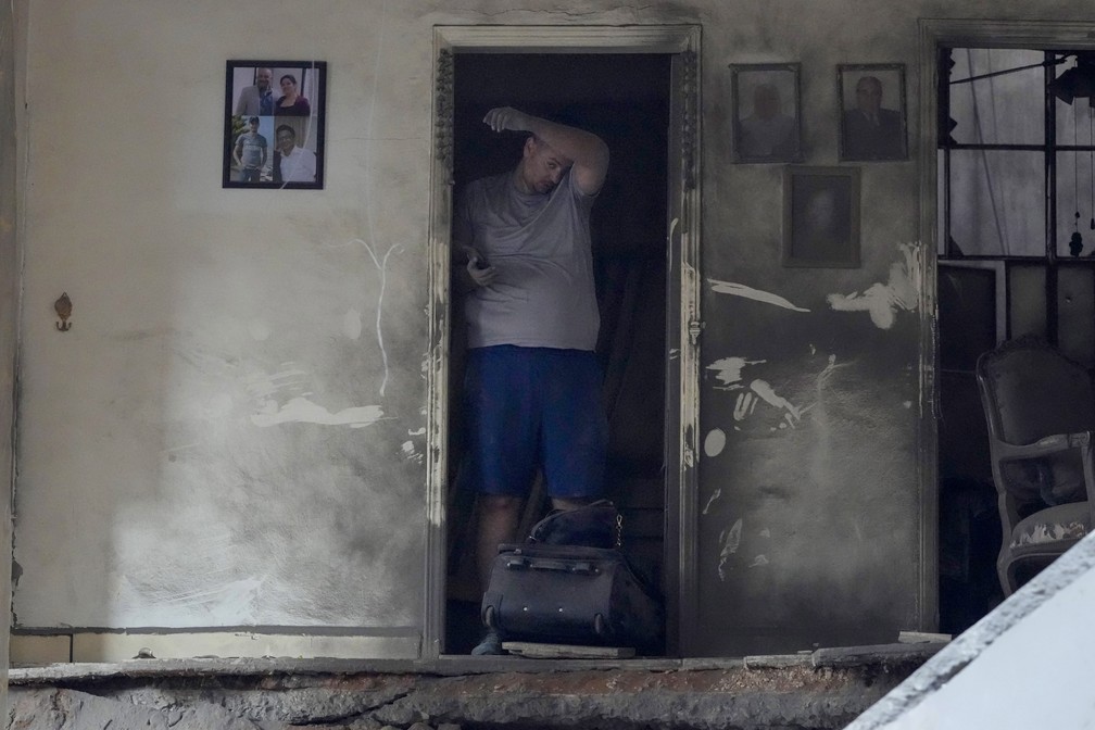 Um morador de um prédio danificado em um ataque aéreo israelense retorna para recolher os pertences de sua família no local — Foto: AP/Hassan Ammar