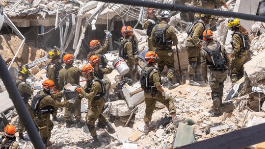 Irã e Israel buscam sobreviventes nos escombros de bombardeios em Teerã e Tel Aviv; veja imagens - As equipes de resgate israelenses vasculharam os escombros de prédios residenciais destruídos por mísseis iranianos, usando cães farejadores e escavadeiras pesadas para procurar sobreviventes.