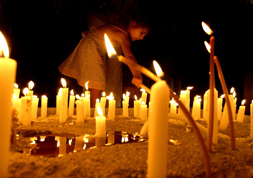Criança coloca vela em memorial para as vítimas do voo Helios 522, que caiu na Grécia em 2005 — Foto: Petros Karadjias/AP
