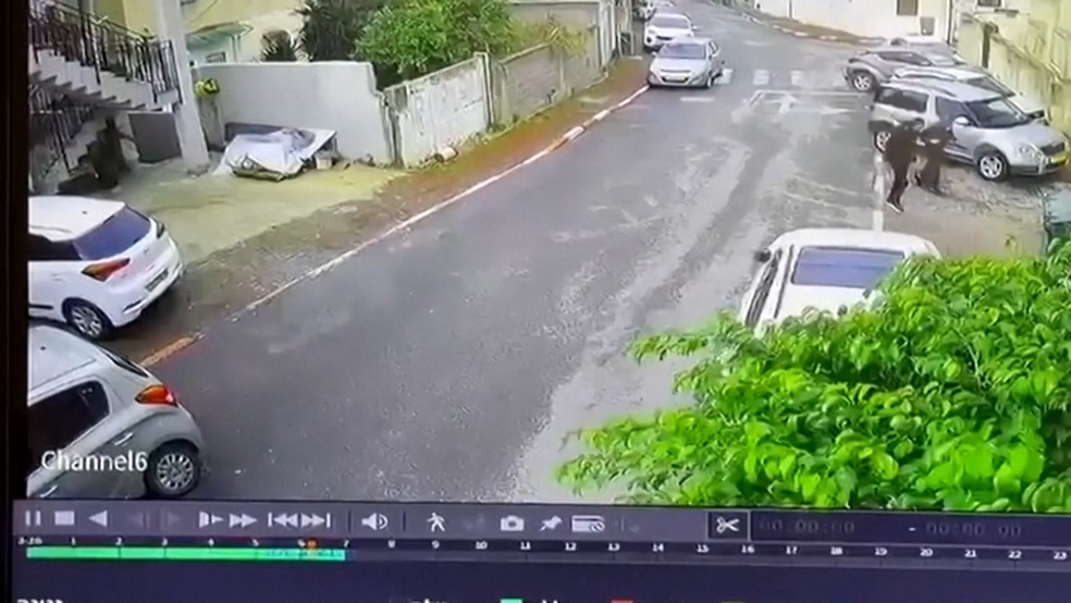 Casal passando apressado pouco antes de míssil atingir carro — Foto: REUTERS