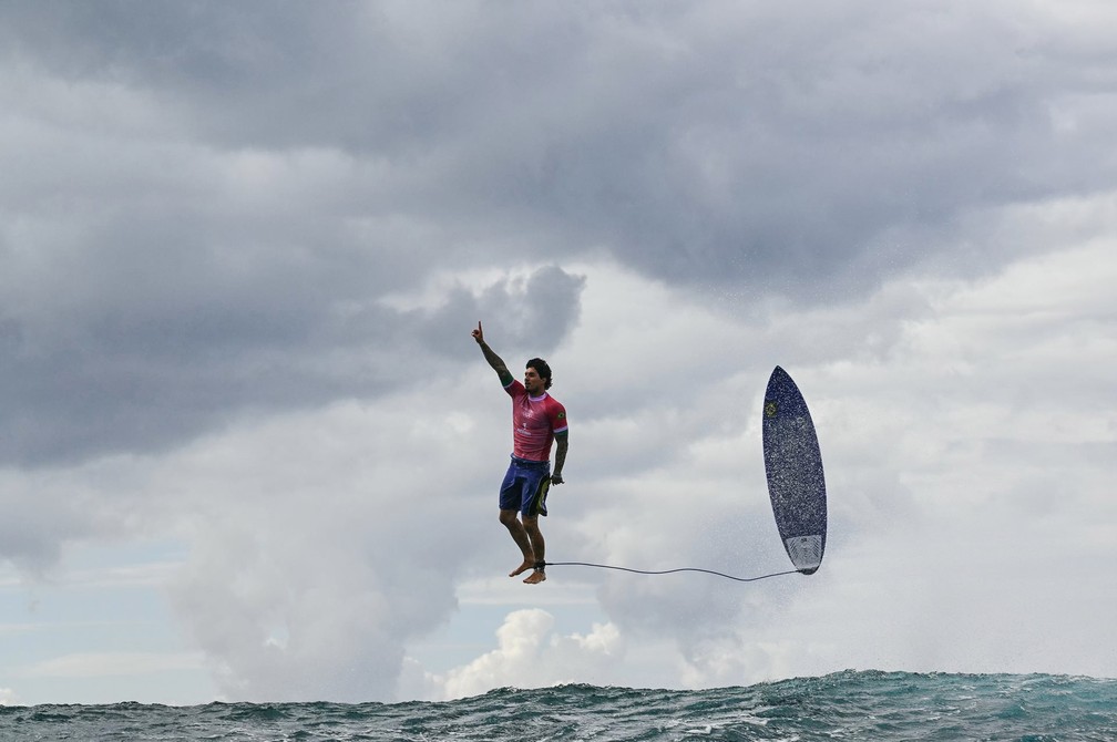 O surfista brasileiro Gabriel Medina parece caminhar no ar após saltar de uma onda durante competição nos Jogos Olímpicos de Paris, que teve a disputa do surfe realizada no Taiti, na Polinésia Francesa. A imagem, que viralizou e rodou o mundo, é de um fotógrafo francês da Agence France Presse e foi vencedora na categoria Individual na região da Ásia-Pacífico e Oceania — Foto: Jerome Brouillet/AFP via World Press Photo/Divulgação