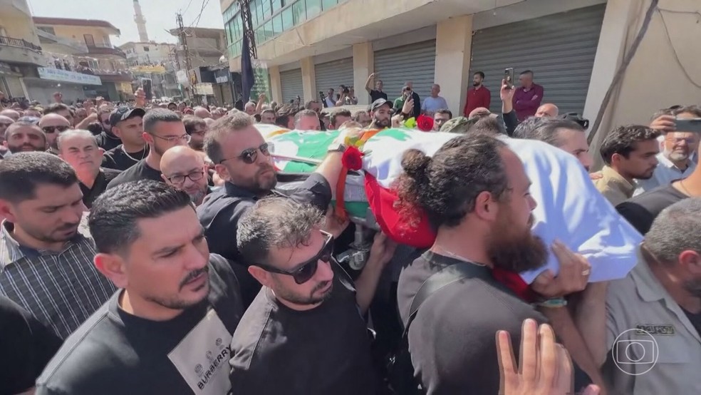 Multidão acompanha enterro de jornalista libanês Issam Abdallah, da agência de notícias Reuters, morto na fronteira com Israel após um míssil atingir sua equipe, em  — Foto: Jornal Nacional/Reprodução