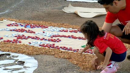 Jovens católicos fazem tapetes com serragem colorida no dia de Corpus Christi em Palmas