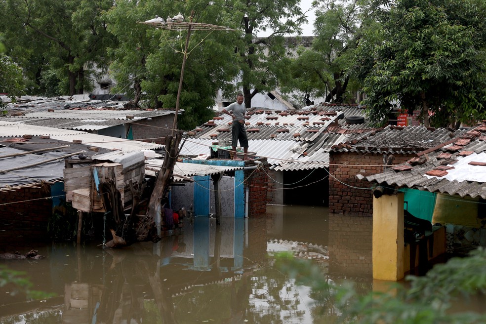 Um morador está no telhado de sua casa alagada após fortes chuvas de monção, nos arredores de Ahmedabad, Índia, em 28 de julho de 2026. — Foto: Amit Dave/ Reuters