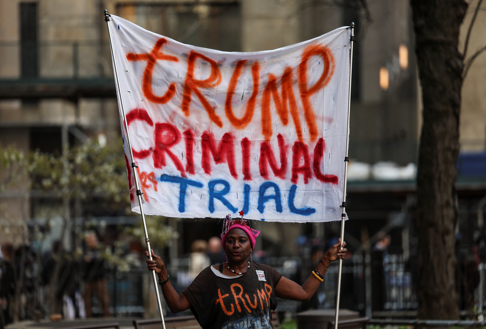 Manifestante carrega cartaz contra Donald Trump próximo ao tribunal onde ele será julgado pela acusação de esconder pagamentos a uma atriz pornô, em 15 de abril de 2024. — Foto: Shannon Stapleton/ Reuters