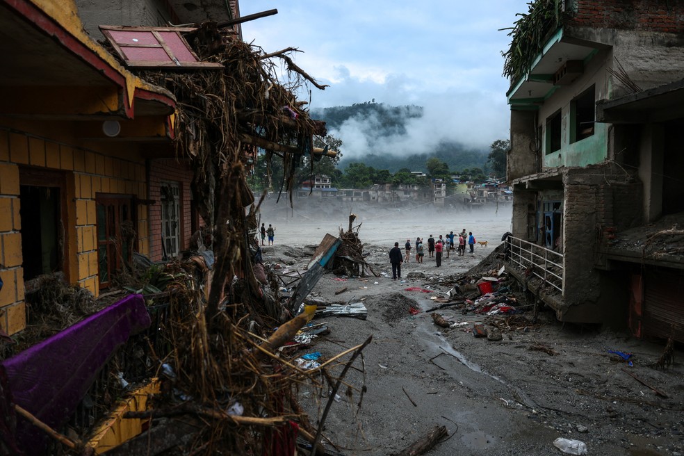 Pessoas observam prédios danificados após as enchentes repentinas e o deslizamento de terra no Nepal. — Foto: Athit Perawongmetha / Reuters