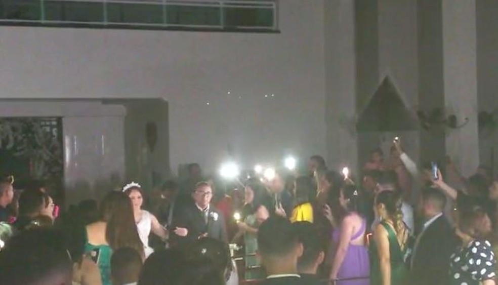 Convidados usaram lanterna de celulares para iluminar o corredor na entrada da noiva, após falta de energia em igreja de Fortaleza. — Foto: Reprodução