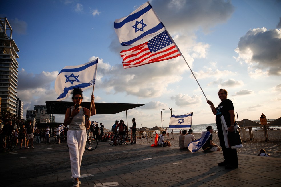 Casal segura bandeiras de Israel e dos Estados Unidos na cidade de Tel Aviv em 20 de setembro de 2023 — Foto: Shir Torem/REUTERS