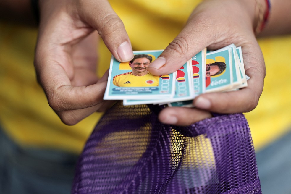 Homem segura adesivos com imagens dos dois candidatos à presidência no segundo turno da Colômbia, imitando figurinhas da Copa do Mundo, em 4 de junho de 2026. — Foto: Jose Vargas/ Reuters