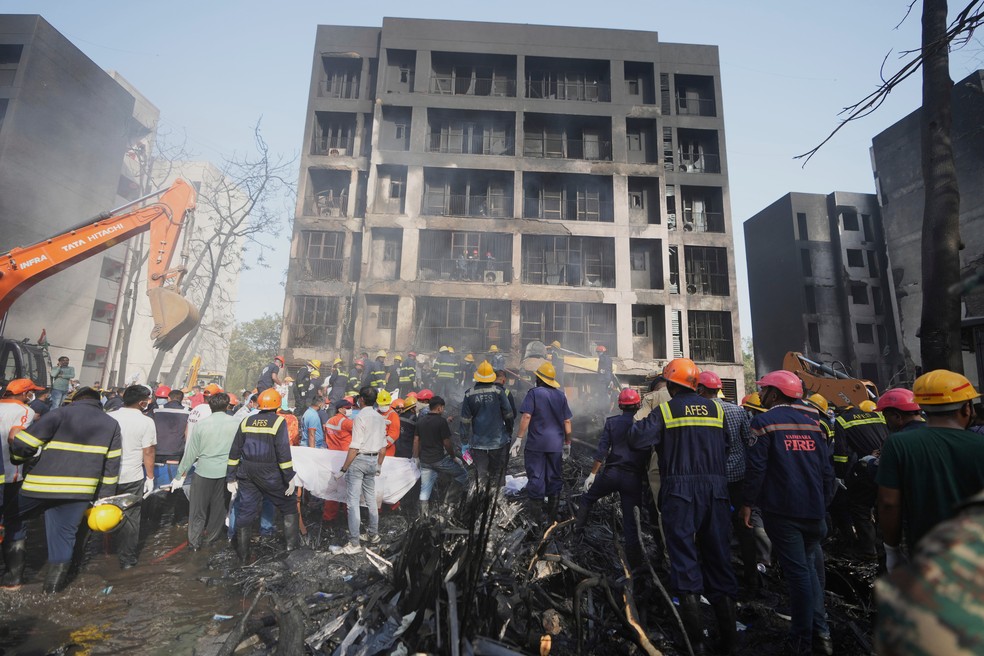 Equipes de resgate e moradores em local de queda de avião na Índia — Foto: AP Photo/Ajit Solanki