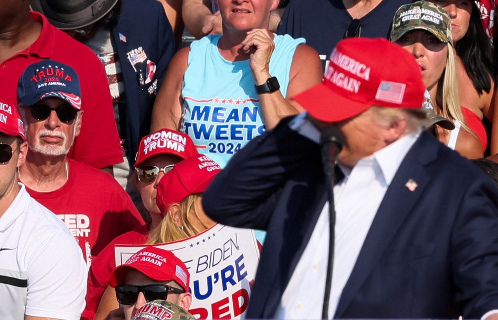 Donald Trump leva mão à orelha assim que começam os sons de tiros em comício — Foto: REUTERS/Brendan McDermid