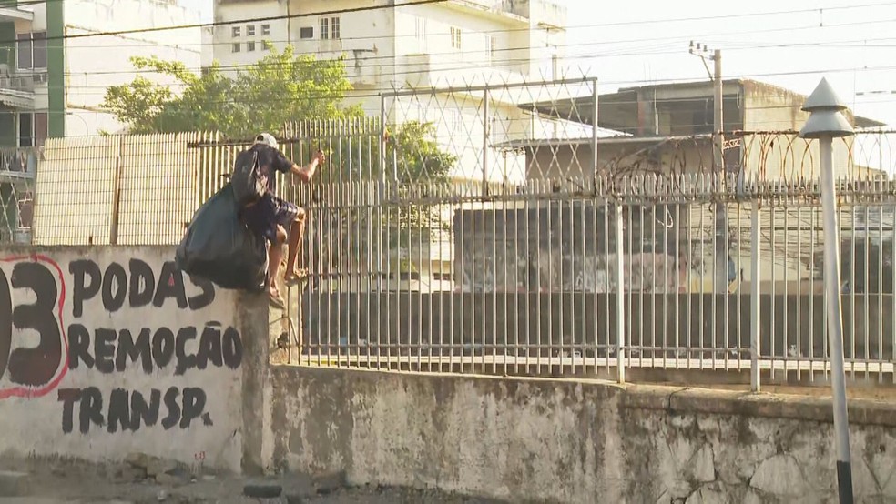 Homem pula muro de estação da Supervia com um saco enorme — Foto: Marcelo Alves/ TV Globo