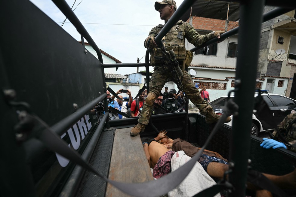 Corpos são transportados em veículo da Polícia Civil após operação contra o CV na Penha, no Rio - 28/10/2025 — Foto: Mauro Pimentel/AFP