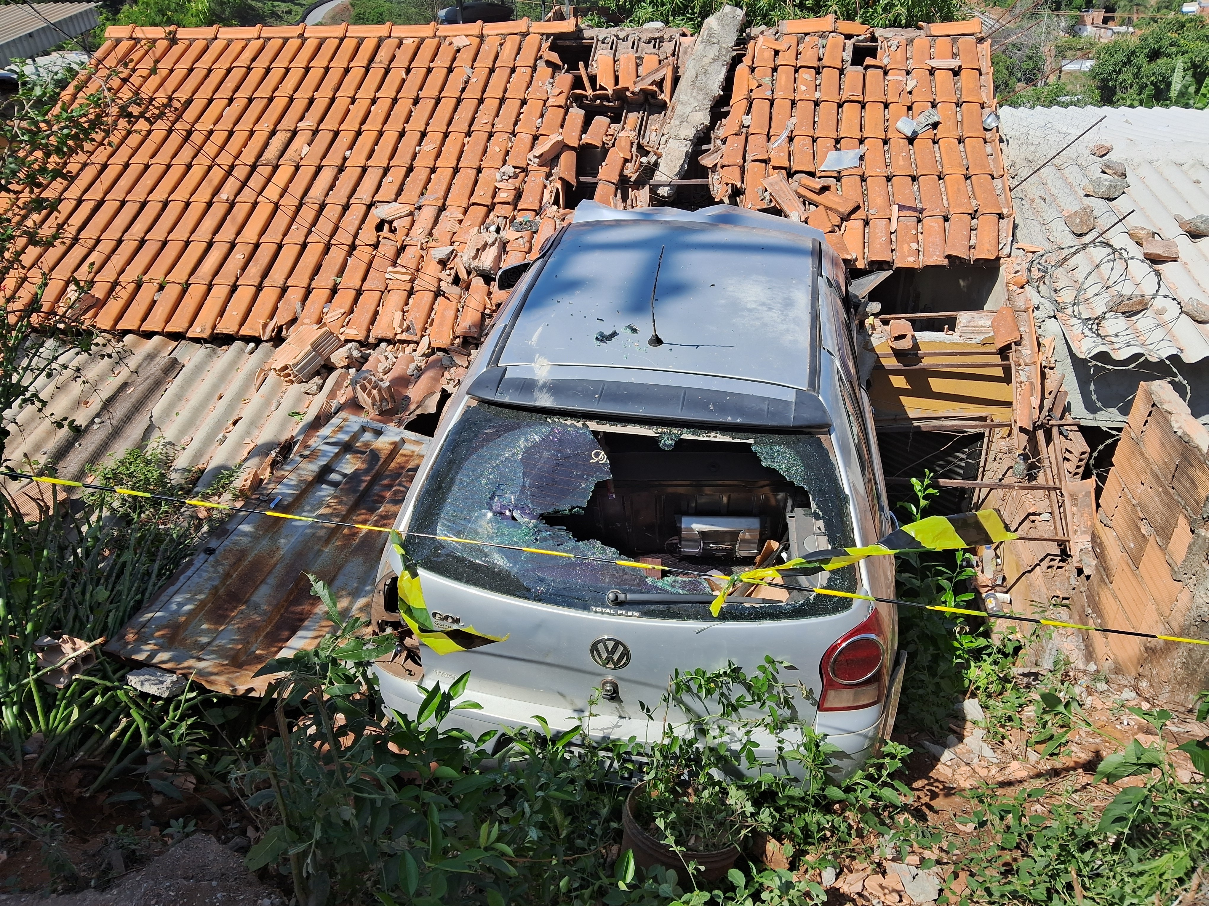 Carro bate em muro e fica pendurado sobre casa na Grande BH