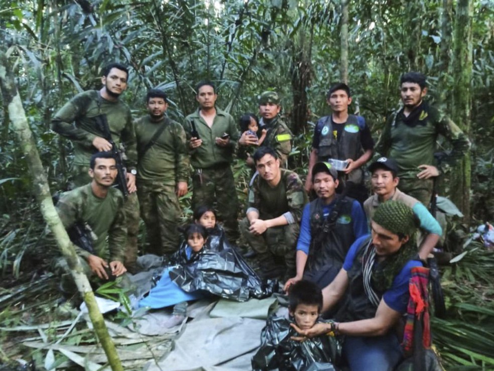 Lesly Jacobombaire Mucutuy ( no centro, atrás do irmão mais novo) posa para foto com irmãos, militares e indígenas que buscavam pelas crianças na selva colombiana, em 9 de junho de 2023.  — Foto: Forças Armadas da Colômbia via AP 