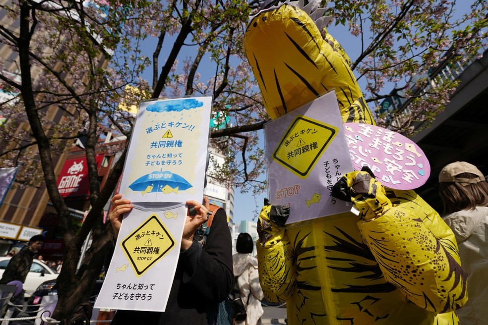 Cartazes com a frase “Aprenda sobre a guarda compartilhada e proteja seus filhos”, exibidos em um comício para protestar contra a entrada em vigor da guarda compartilhada pós-divórcio em 1º de abril, no bairro de Shinjuku, em Tóquio. — Foto: Kazuhiro Nogi/AFP