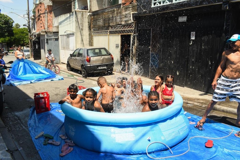 Crianças se refrescam em piscina inflável no bairro A.E. Carvalho, na Zona Leste de SP — Foto: EDI SOUSA/ATO PRESS/ESTADÃO CONTEÚDO