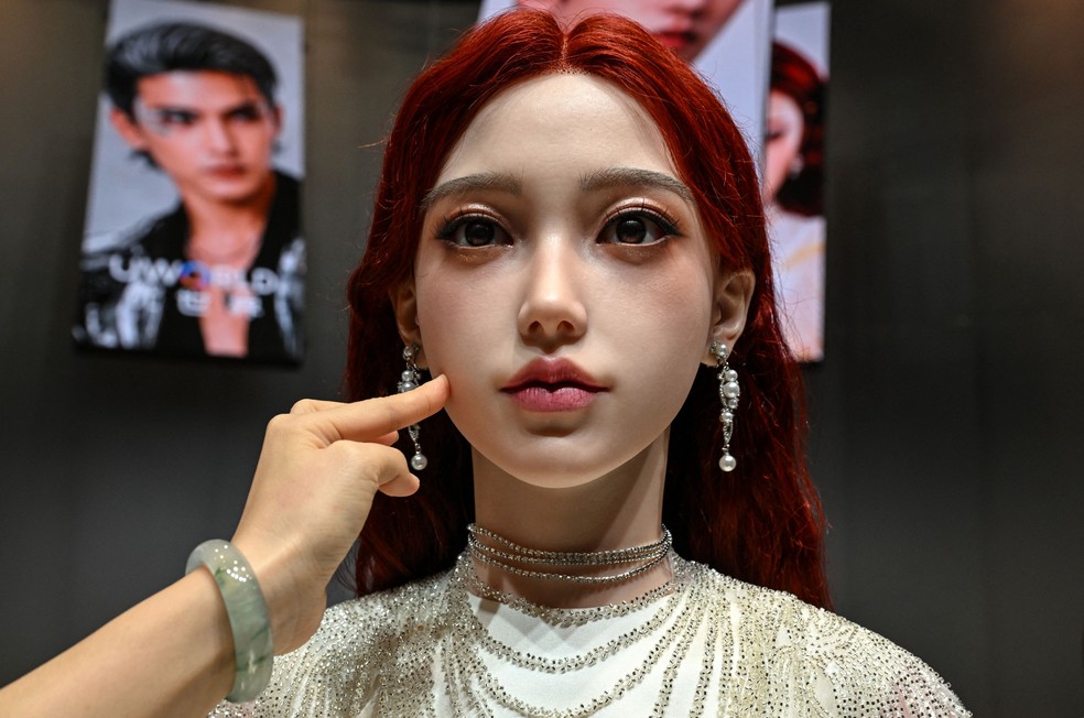 Uma mulher toca o rosto de um robô humanoide durante o lançamento do robô humanoide U1, produzido pela UWORLD, uma marca da UBTECH Robotics, em Shenzhen, na província de Guangdong, na China, em 30 de junho de 2026. — Foto: Adek Berry/AFP