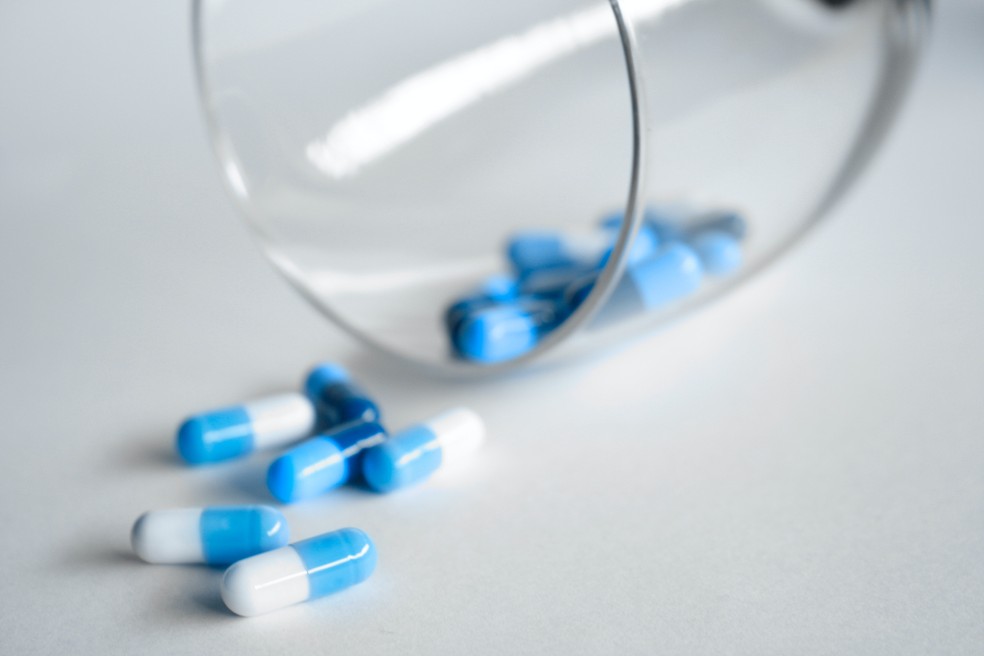 IMAGEM ILUSTRATIVA: pílulas de medicamentos espalhadas sobre uma mesa e um copo. — Foto: Pexels/Divulgação.