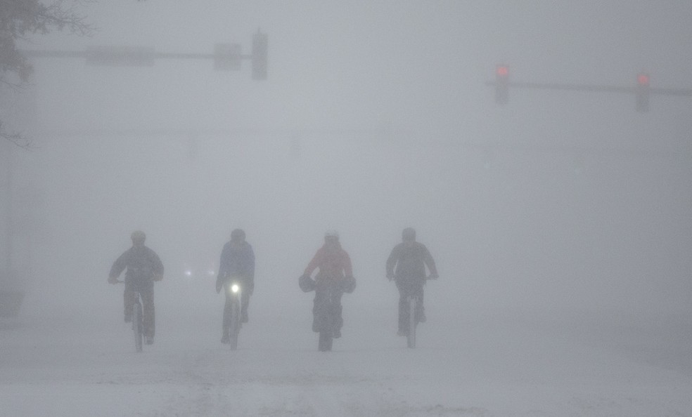 Ciclistas enfrentam a neve em Wichita, no Kansas, durante a tempestade no domingo (5) — Foto: AP