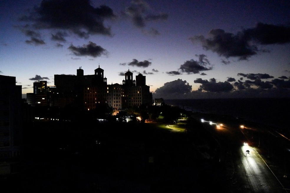 Carros passam em frente ao Hotel Nacional, em Havana, com tudo às escuras. — Foto: Reuters via BBC