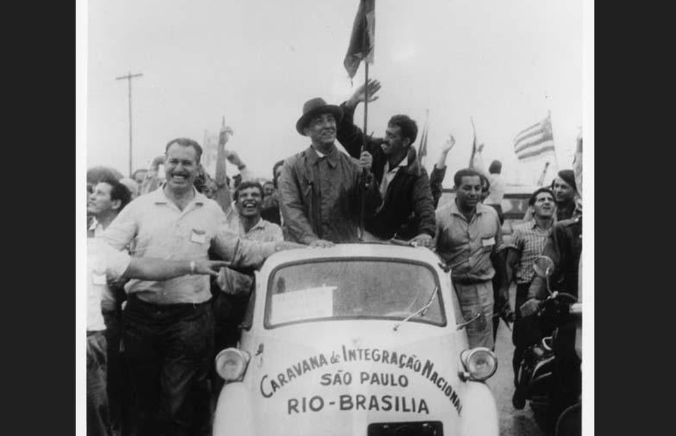 Presidente Juscelino Kubitschek, com a bandeira na mão, entra em Brasília à frente da Caravana de Integração Nacional em um romi-isetta — Foto: Fundação Romi/Arquivo