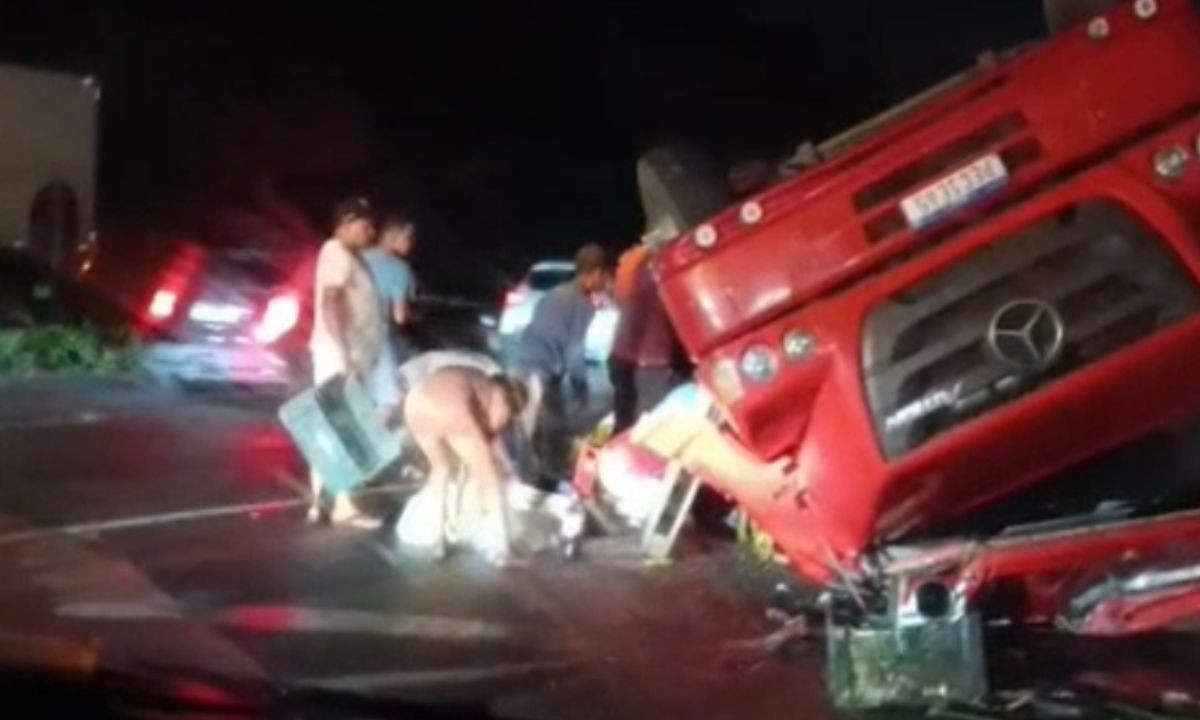 Caminhão que levava refrigerantes tomba em rodovia e população saqueia carga enquanto motorista aguarda atendimento médico