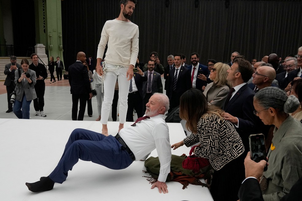 O presidente Lula se equilibra sobre os braços ao tentar copiar movimento de acrobata durante visita a exposição em Paris, na França, com o presidente francês, Emmanuel Macron, em 6 de junho de 2025. — Foto: Michel Euler/ Pool via Reuters